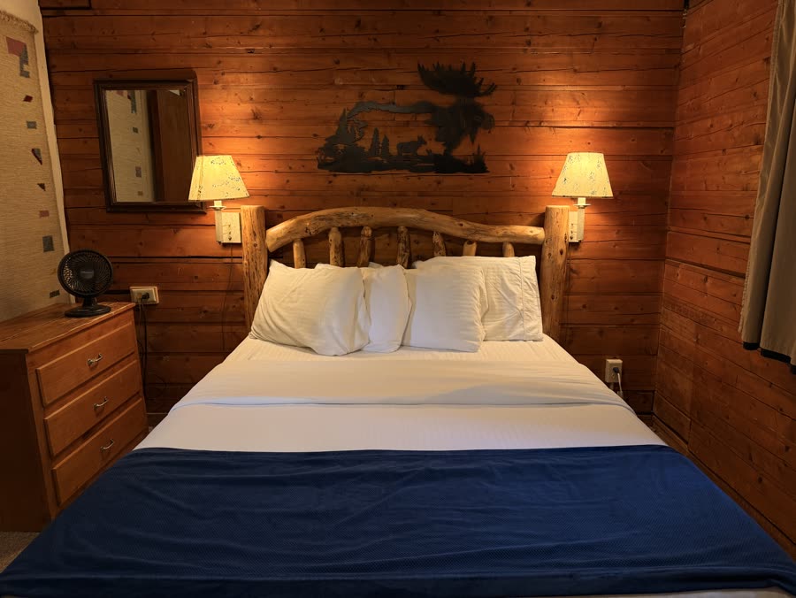 Cabin bedroom with a wooden bed frame and pine walls
