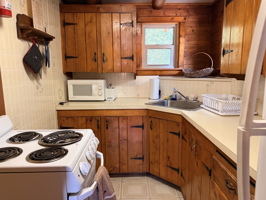 Compact cabin kitchen with pine cabinets and a full stove