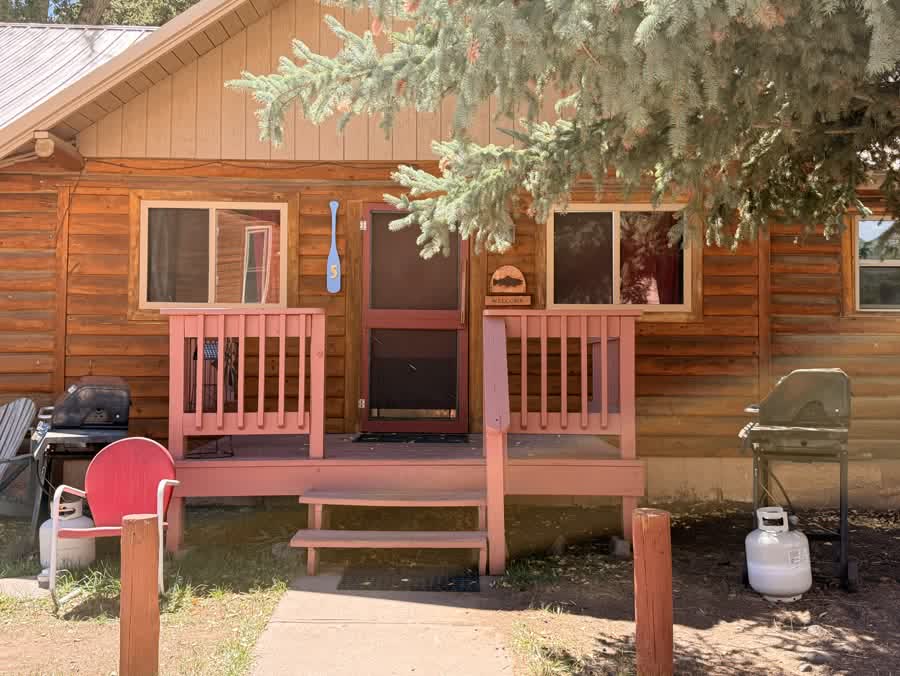 Cabin porch with railings and a grill