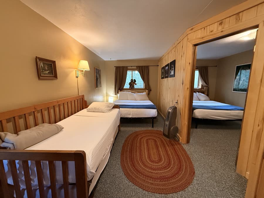 Cabin room with several beds and a braided rug