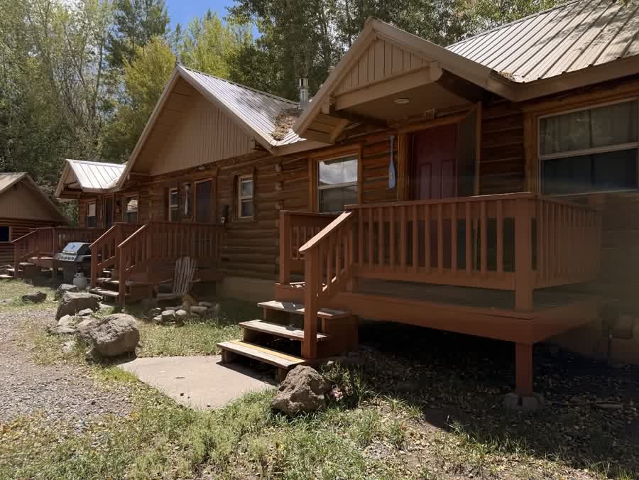 Log cabins with covered porches under evergreens