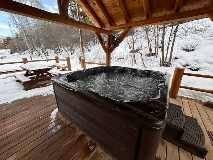 Open-air hot tub steaming on a snowy deck