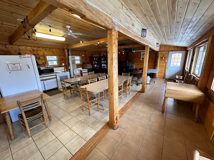 Large recreation room with long tables and a kitchen