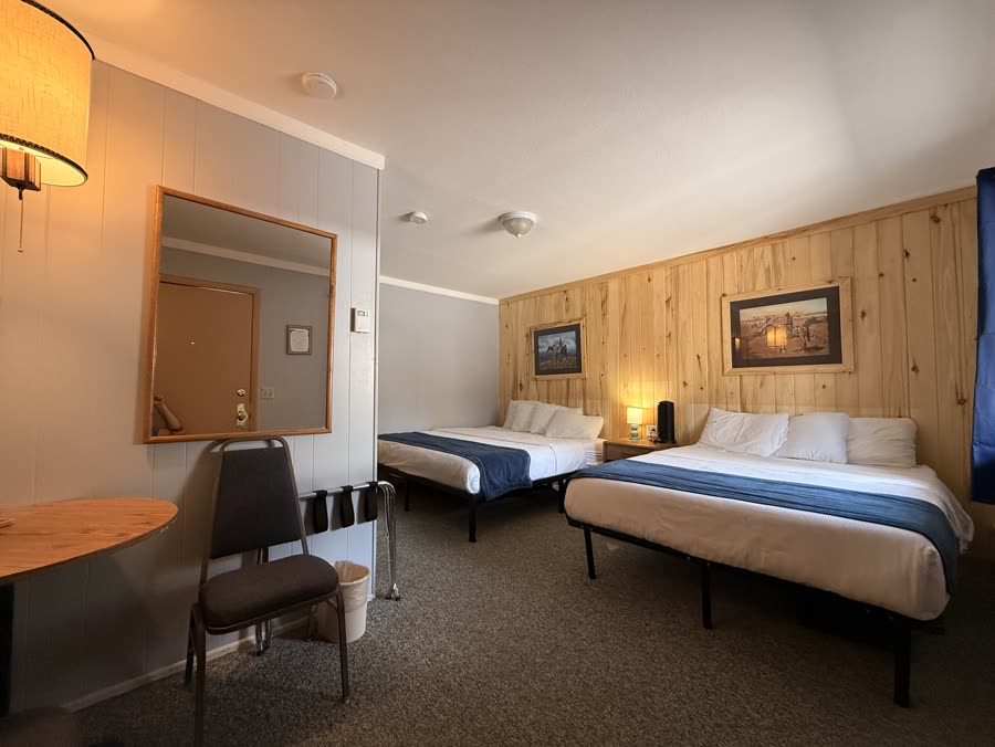 Lodge room with two beds, pine walls and a bedside lamp