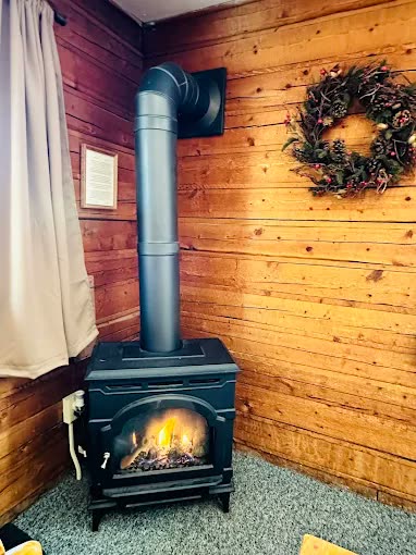 A lit wood stove against a log wall
